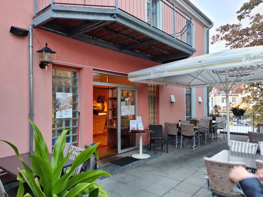 Eingang eines Restaurants mit überdachter Außenterrasse und gemütlicher Sitzgelegenheit